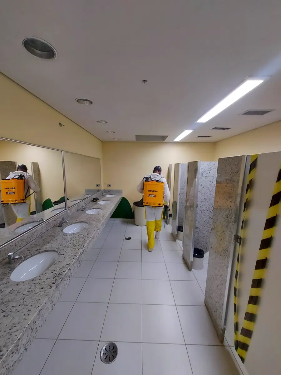 Técnico da Insetivan realizando dedetização em banheiro coletivo com pulverizador costal